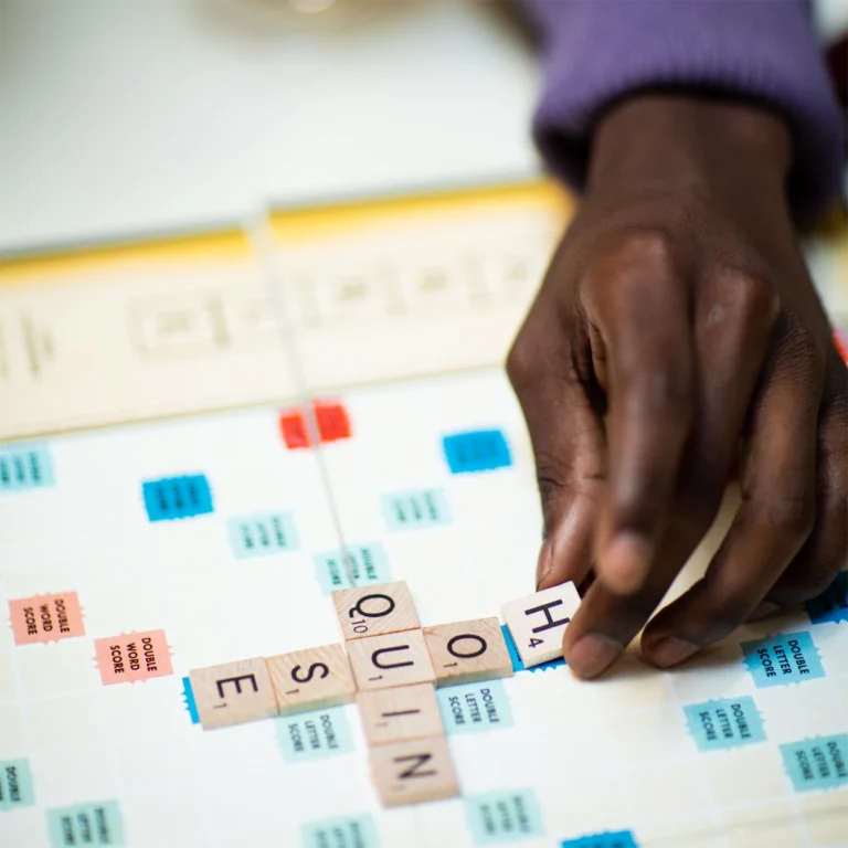 Photo of man's hand playing Scrabble at The 'Quin House